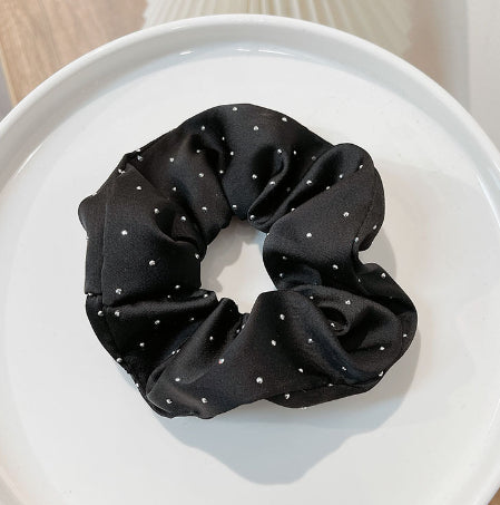 Black scrunchie with silver studs on a white surface