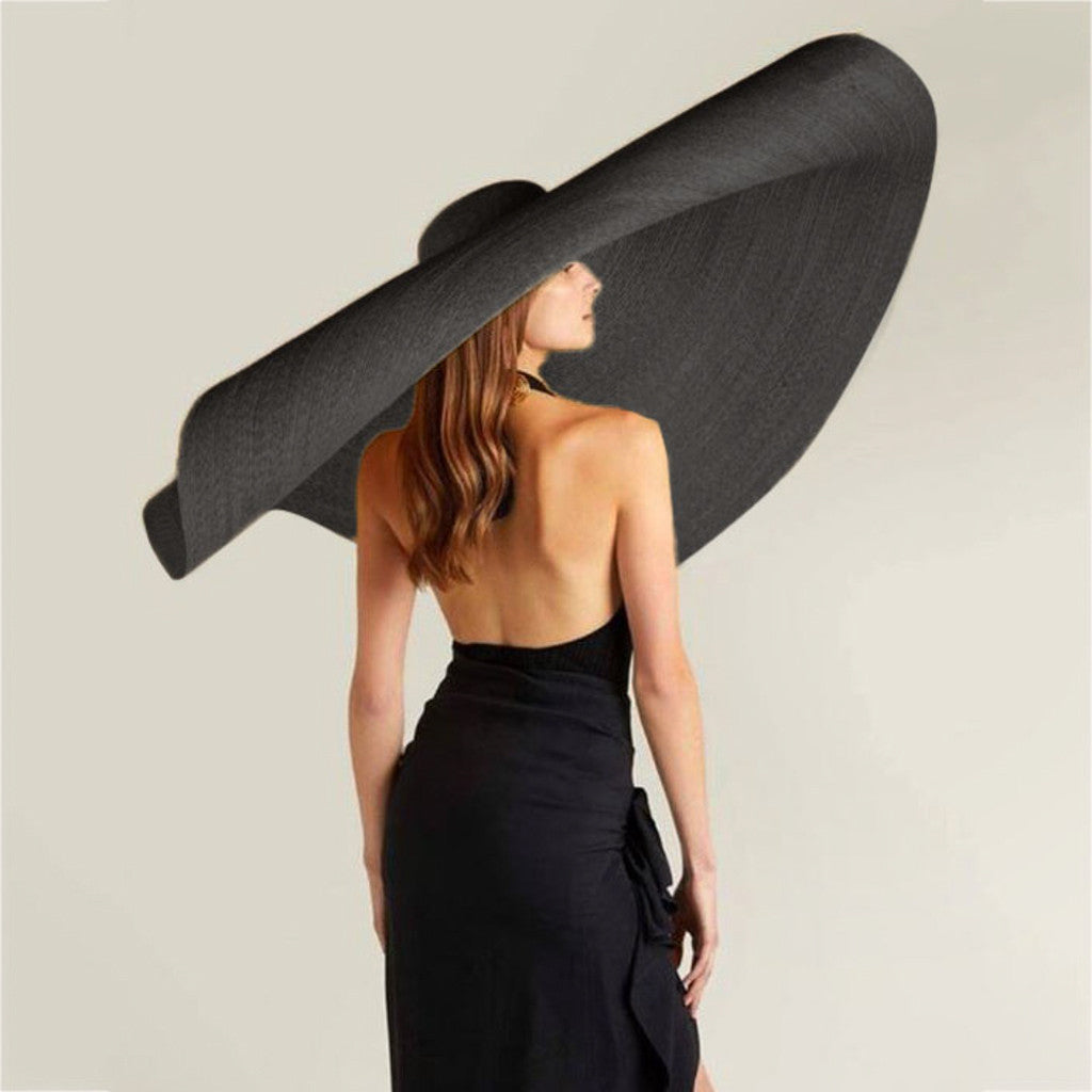 Woman wearing wide-brim white straw hat outdoors, shielding face from sun with flat-eave design