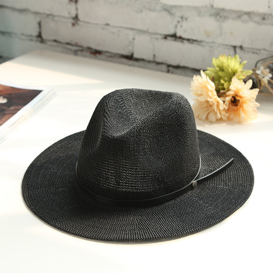 Black straw hat on a white surface with a blurred background
