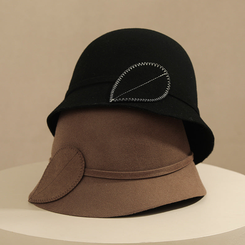 Two hats, one black and one brown, on a beige background.