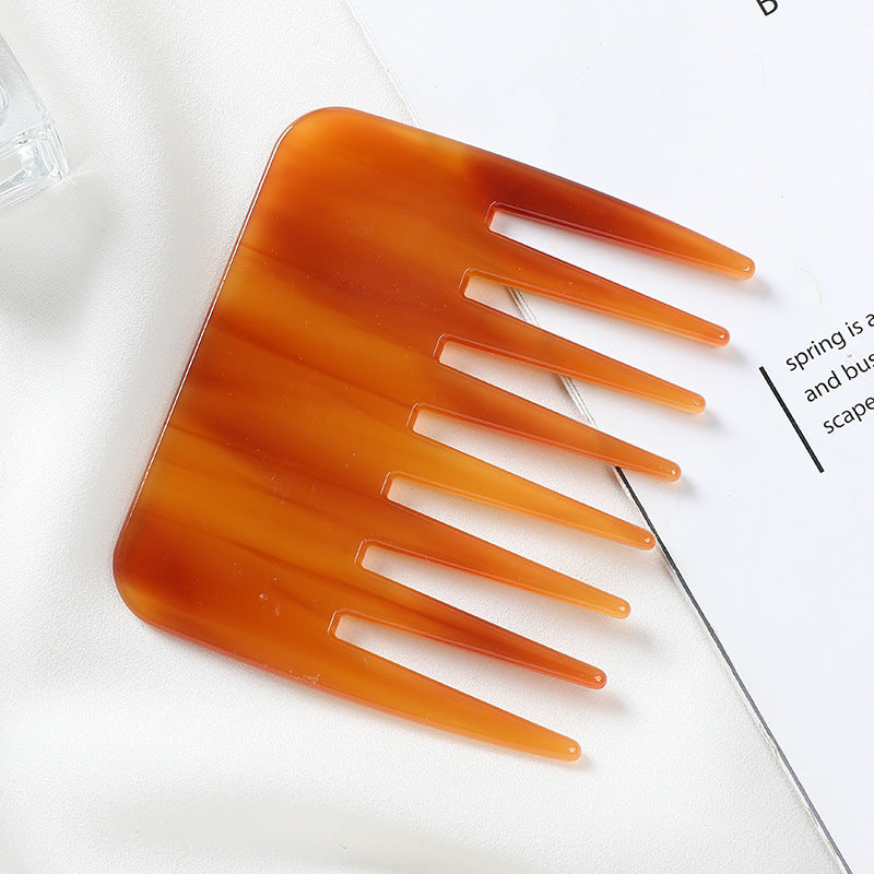 Orange comb on a white surface with text partially visible Marble-finish cellulose acetate hair comb, anti-static and gentle on hair