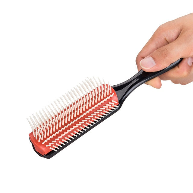 Hairbrush with red and white bristles held by a hand on a white background