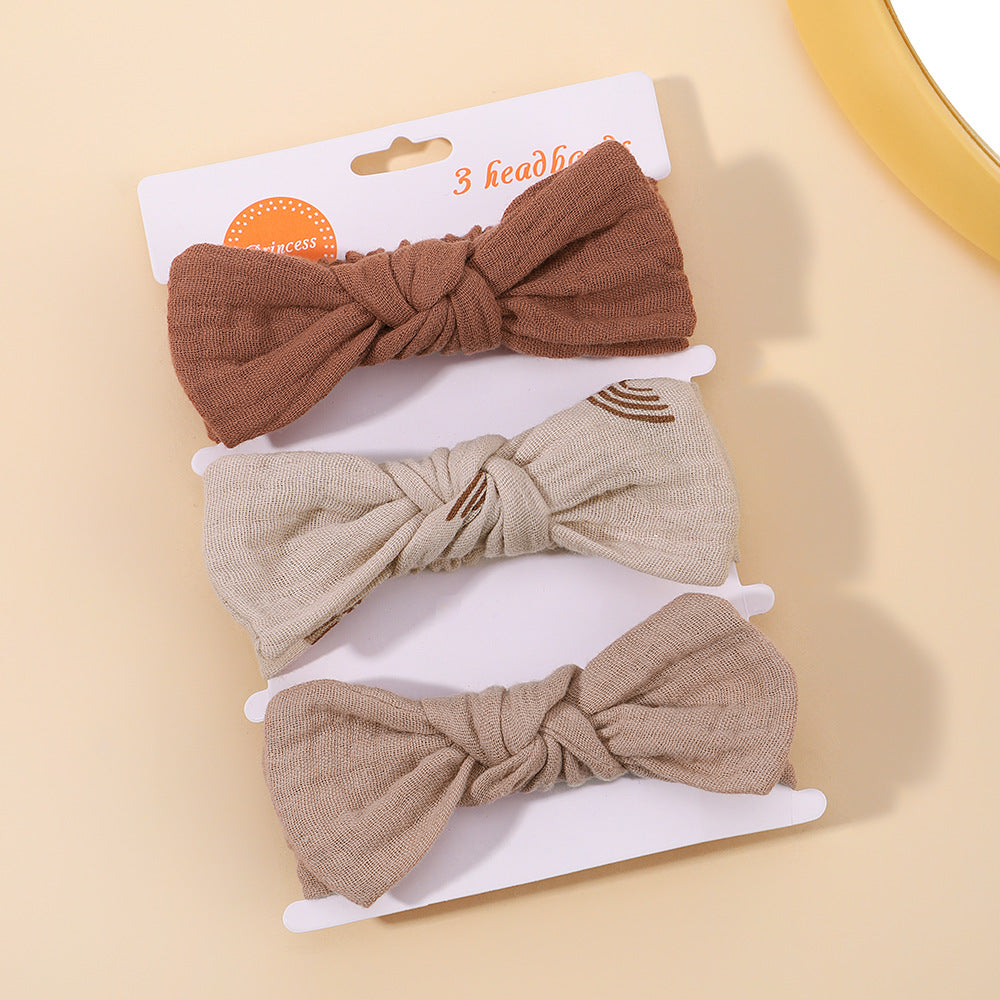 Three brown hair bows on a white card with a beige background