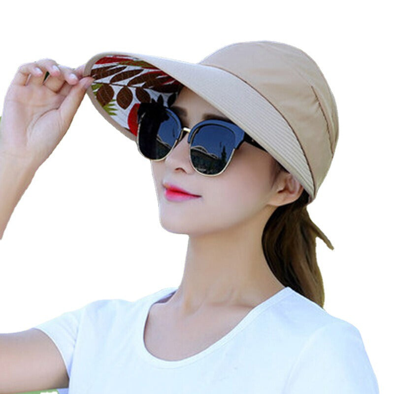 Woman wearing a beige sun hat with floral design and sunglasses on a white background