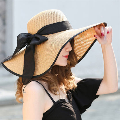 Women's wide-brim floppy straw sun hat with bow detail on white background