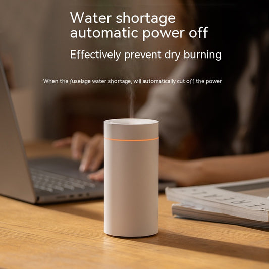White ceramic mug with steam on a wooden table, surrounded by a blurred background of a person using a laptop.